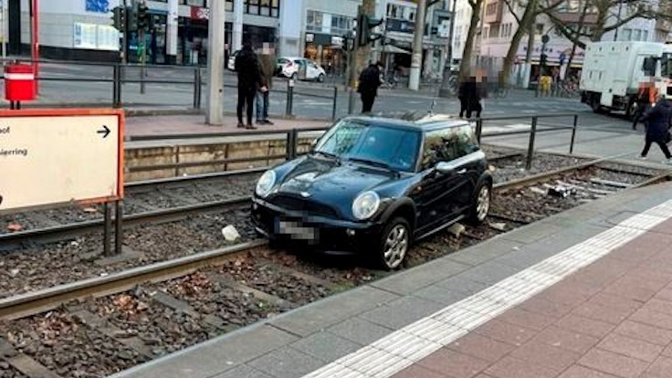 Ein Auto liegt in einem Gleisbett einer Straßenbahnhaltestelle.