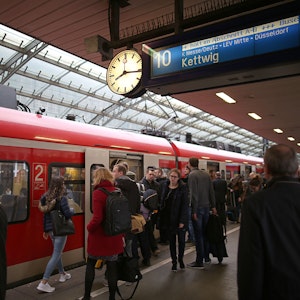 Fahrgäste stehen am Hauptbahnhof Köln vor einer S-Bahn