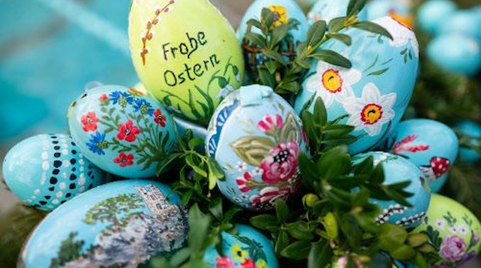 Bunt bemalte Ostereier sind am 10. April 2022 an einem Osterbrunnen angebracht, eines trägt die Aufschrift „Frohe Ostern“.