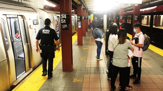 Das undatierte Symbolfoto zeigt eine U-Bahn-Station mit zwei haltenden Bahnen und mehreren Menschen, darunter ein Polizist in Uniform.