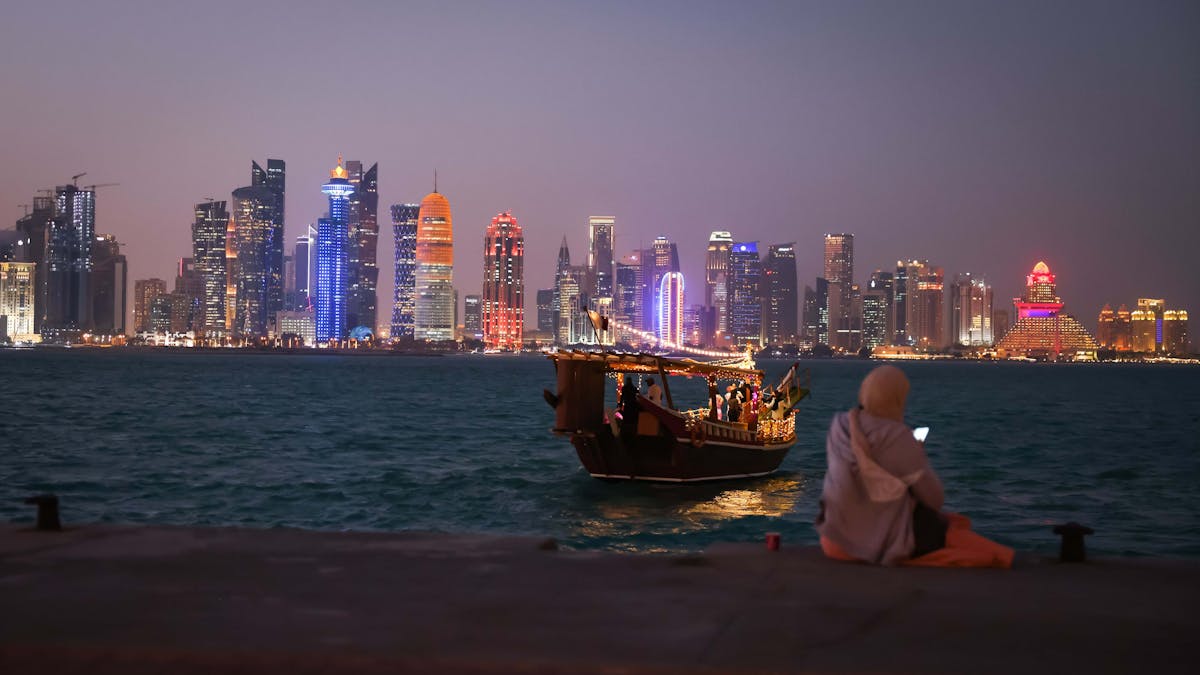 Eine Frau schaut auf ihr Smartphone vor der Skyline von West Bay Doha in Katar