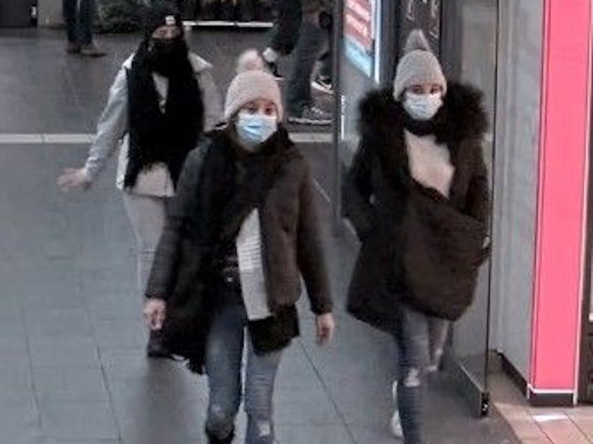 Drei junge Frauen schlendern scheinbar durch den Bahnhof.