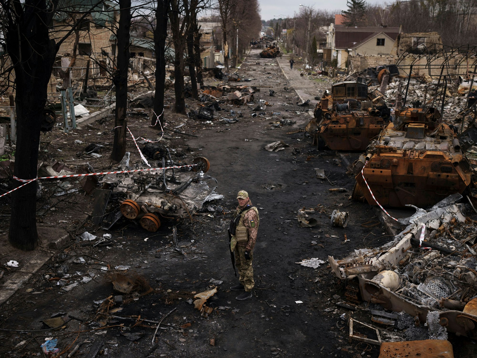 Ein ukrainischer Soldat steht neben zerstörten russischen Panzer inButscha am Stadtrand von Kyjiw.