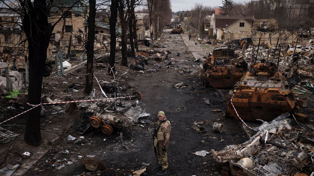 Ein ukrainischer Soldat steht neben zerstörten russischen Panzer in&nbsp;Butscha am Stadtrand von Kyjiw.