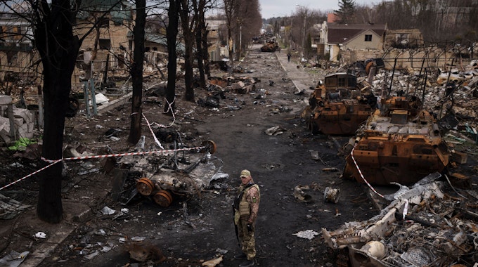 Ein ukrainischer Soldat steht neben zerstörten russischen Panzer in Butscha am Stadtrand von Kyjiw.