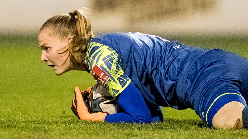 Manon Klett hält den Ball in den Händen und liegt im Spiel gegen den VfL Wolfsburg auf dem Boden