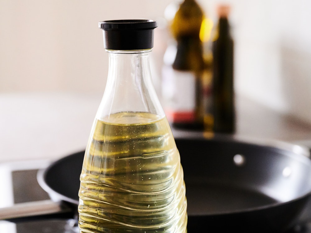 In eine Glasflasche abgefülltes Sonnenblumenöl steht neben einer Pfanne in einer Küche. Die Nachfrage nach Speiseöl und Mehl in Deutschland ist nach Beginn des Ukraine-Krieges zeitweise stark gestiegen.