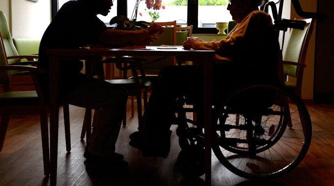 Ein Azubi zum Altenpfleger unterhält sich im Pflegeheim Eilenriedestift in Hannover mit einer Seniorin.