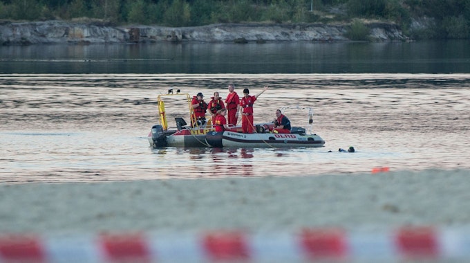 Einsatzkräfte der Feuerwehr und des DLRG fahren in Booten auf einem See.