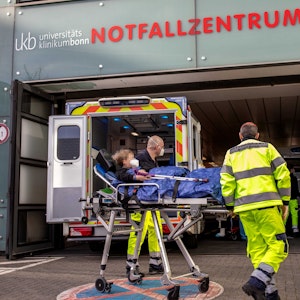 Zwei Männer bringen ein kleines Kind auf einer rollenden Krankentrage in das Notfallzentrum Bonn.