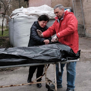 Ein ukrainisches Paar steht am 18. April vor dem Leichnam ihres Sohnes, der in Nähe von Butscha von ukrainischen Soldaten erschossen sein soll. Russlands Präsident Wladimir Putin hat jener Brigade, der massenhafte Tötungen in der Stadt vorgeworfen wird, nun einen Ehrentitel verliehen.