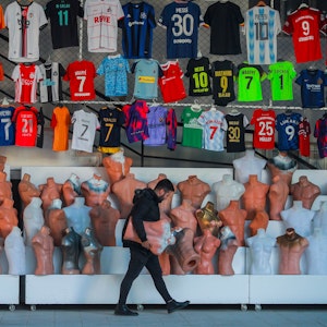 Verkäufer vor seinem Verkaufsstand mit Fußball-Trikots.