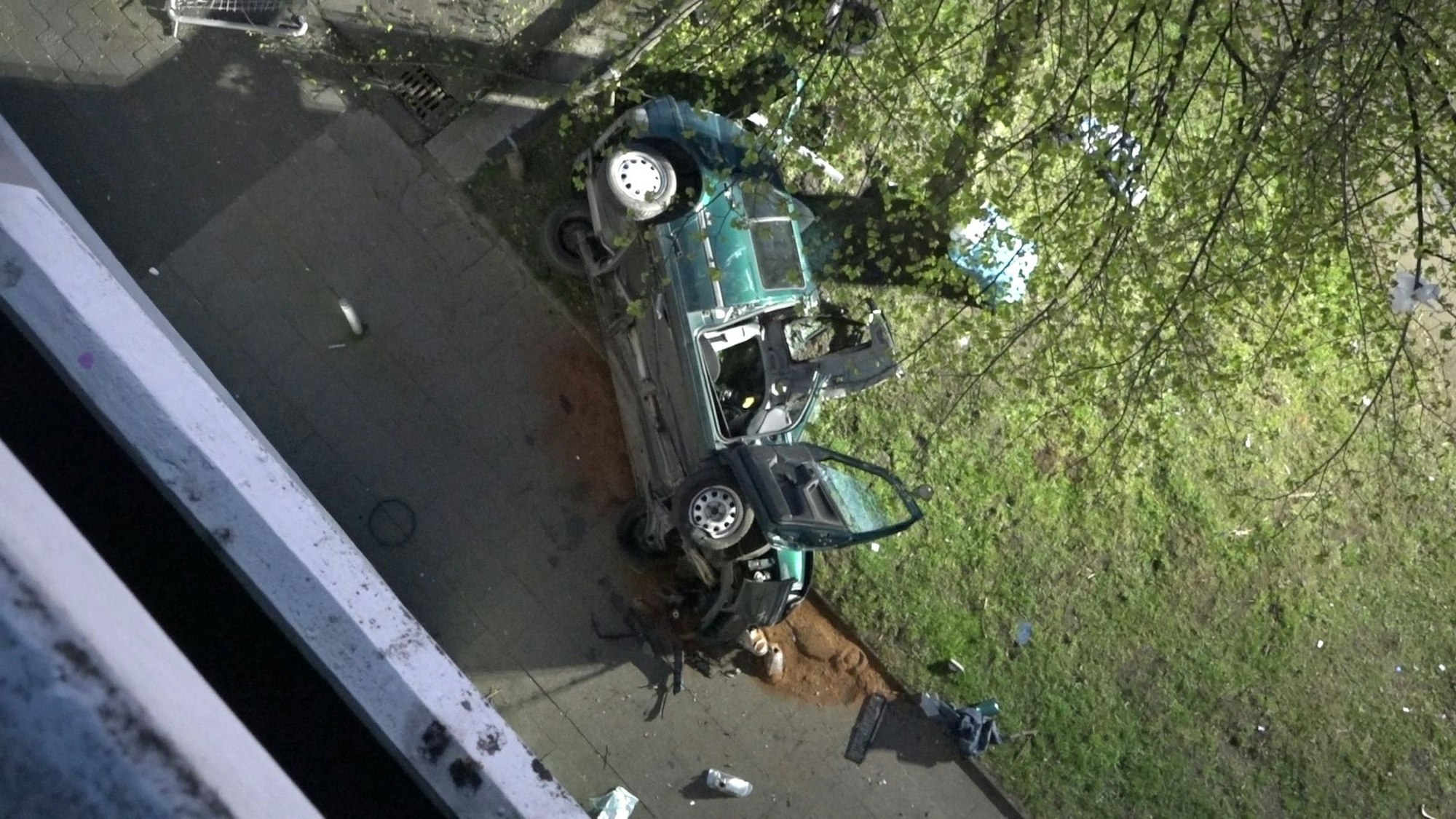 Das Wrack einesAutos liegt neben einem Parkhaus. Zwei junge Männer sind am Ostersonntag in Essen mit einem Auto aus der obersten Etage eines Parkhauses gestürzt und ums Leben gekommen.