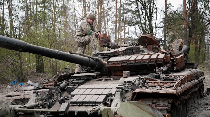 Ein ukrainischer Soldat inspiziert am 19. April 2022 einen russischen Panzer.