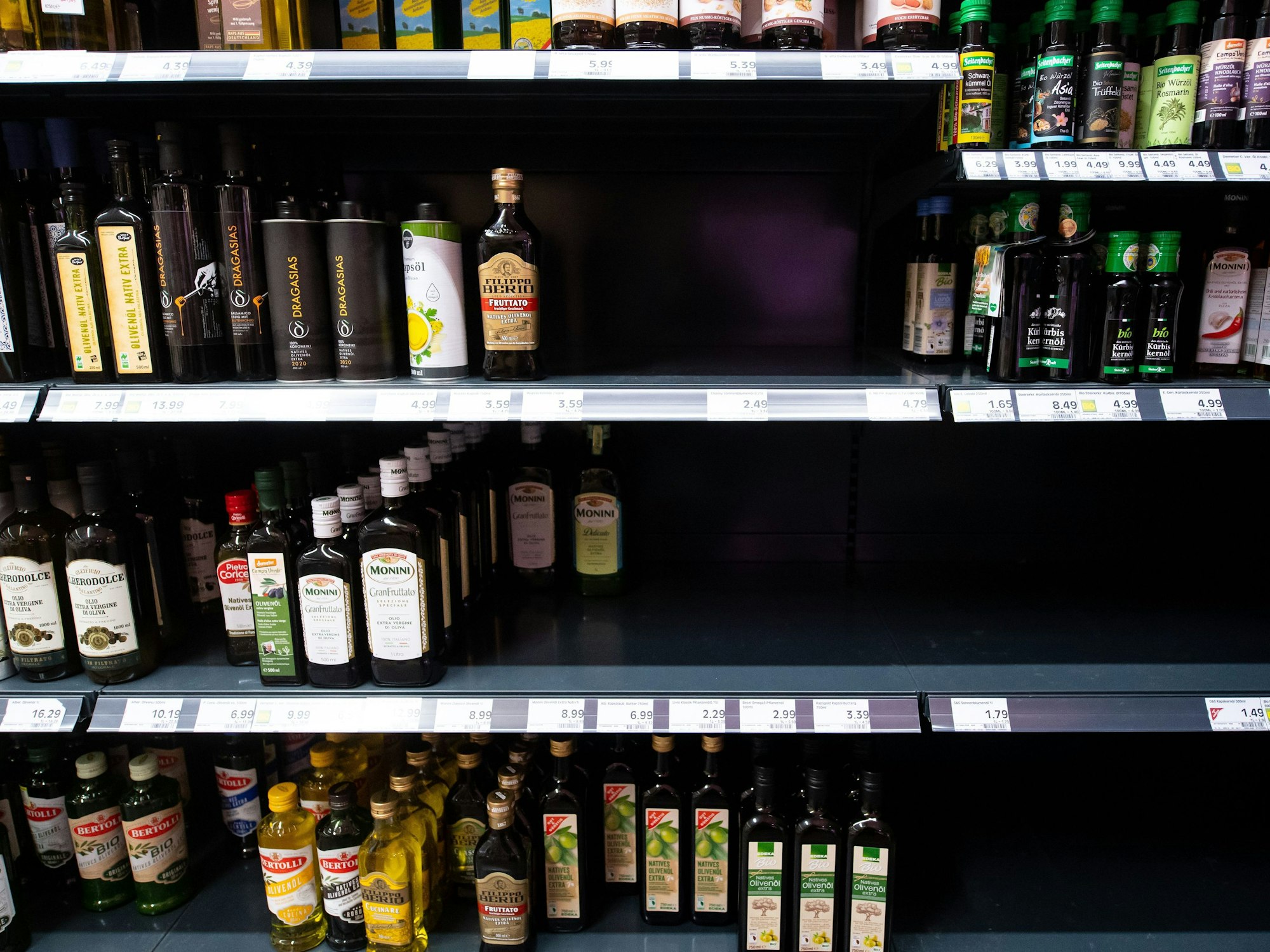 Flaschen mit Öl stehen in einem Regal in einem Supermarkt.