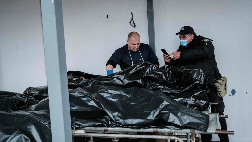 Polizeibeamte fotografieren am 18. April für Ermittlungen einen der Toten, die in Butscha gefunden worden sind. Russischen Streitkräften wird vorgeworfen, in der Stadt zahlreiche Kriegsverbrechen begangen zu haben.