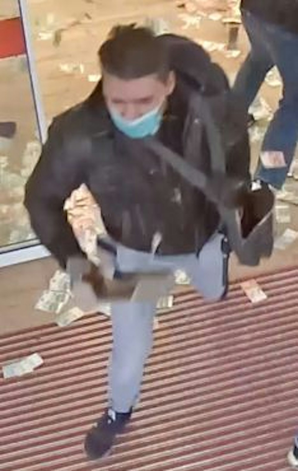 Ein Mann rennt aus einer Bankfiliale, auf dem Boden hinter ihm liegen unzählige Geldscheine.