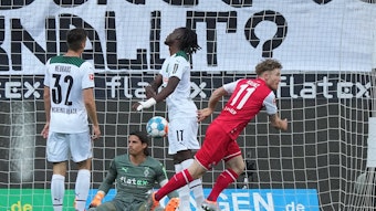 Gladbach-Schlussmann Yann Sommer (2.v.l.) sitzt nach einem Gegentreffer im Derby gegen den 1. FC Köln (16. April 2022) enttäuscht auf dem Boden. Seine Teamkollegen Florian Neuhaus (l.) und Manu Koné (2.v.r.) ärgern sich ebenfalls, Florian Kainz (r.) jubelt. Im Hintergrund ist der Ball im Tor.