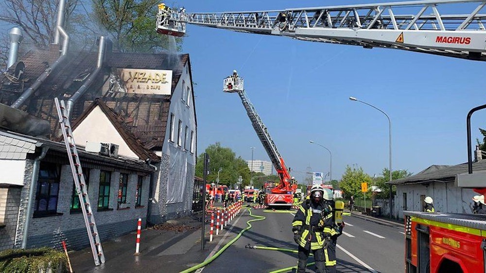 Die Feuerwehr löscht über eine Drehleiter ein brennendes Hausdach.