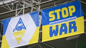 Zwei blau-gelbe Wappen mit Borussia-Logo und Anti-Kriegs-Slogan am 3. April 2022 im Borussia-Park.