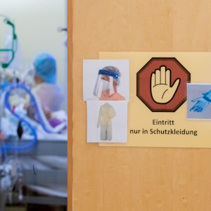 Ein Warnschild zum Tragen von Schutzkleidung hängt auf der Intensivstation des Gemeinschaftskrankenhauses Havelhöhe an der Tür eines Covid-19-Patientenzimmers.