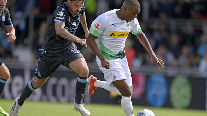 Borussia Mönchengladbach trifft in der Sommer-Vorbereitung auf den TSV 1860 München. Das Foto zeigt Gladbachs Alassane Plea (r.) bei einem früheren Testspiel am 13. Juli 2019 im Zweikampf gegen Dennis Erdmann (l.).