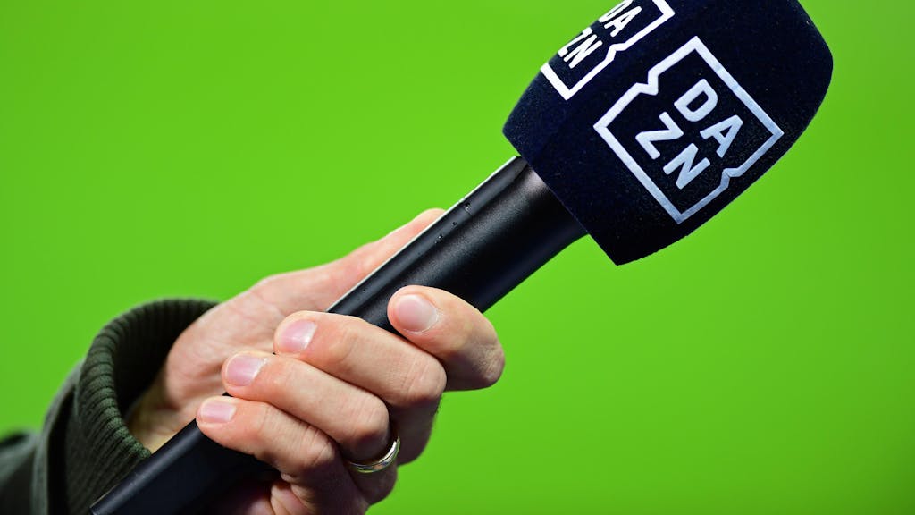 Die Hand eines Reporters hält bei einem Interview vor dem Spiel ein Mikrofon mit der Aufschrift DAZN.