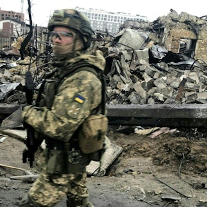 Das Bild zeigt einen ukrainischen Soldaten am 0. April 2022, der an den Trümmern zerstörter Häuser vorbeiläuft.
