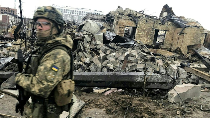 Das Bild zeigt einen ukrainischen Soldaten am 0. April 2022, der an den Trümmern zerstörter Häuser vorbeiläuft.