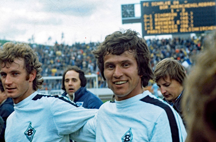 Jupp Heynckes (r.) von Borussia Mönchengladbach mit Team-Kollege Rainer Bonhof (l.) am 16. April 1977 in Gelsenkirchen. Heynckes lächelt.