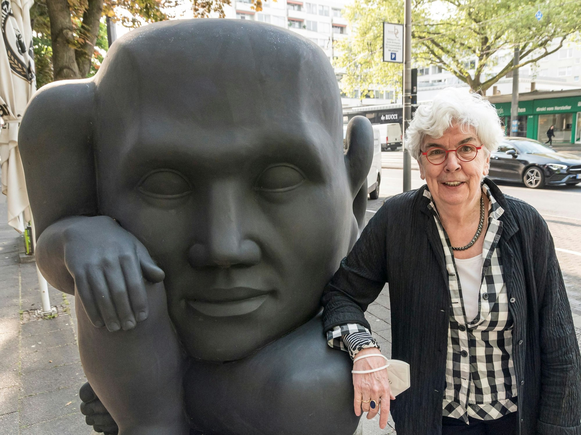 Inhaberin Angelika Herzogenrath neben der schwarzen Skulptur „In die Zukunft horchend“ von Michael Schwarze, die seit 2010 vor der Kölner Kunsthandlung Goyert steht.