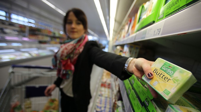 Eine Frau nimmt am 13.03.2015 in Velbert (Nordrhein-Westfalen) in einem Supermarkt von Aldi (Nord) Bio Butter aus dem Regal.