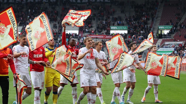 Nach dem Sieg in Augsburg feiern die FC-Profis mit Fähnchen in der Fankurve.
