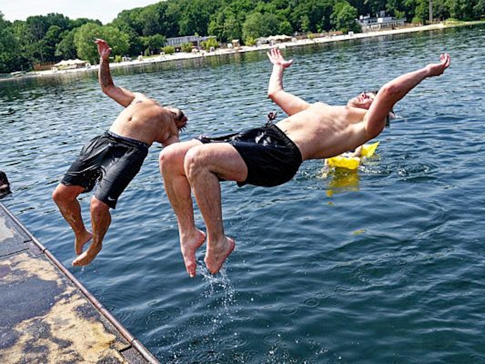 Zwei junge Männer springen am 18. Juni 2021 in den Fühlinger See.