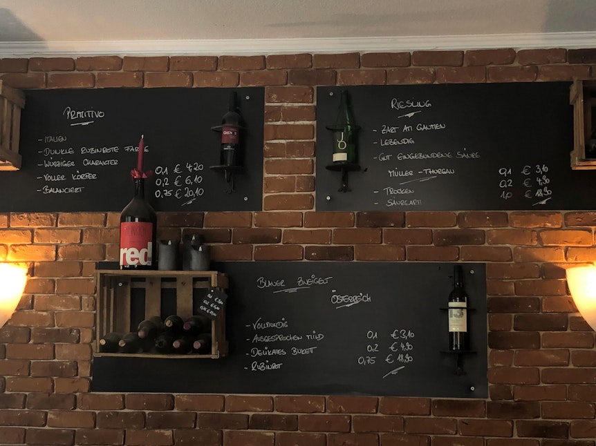 Weinregale hängen an der Wand im Café Haptilu.