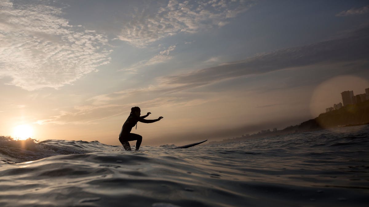Eine Frau surft bei Sonnenuntergang.