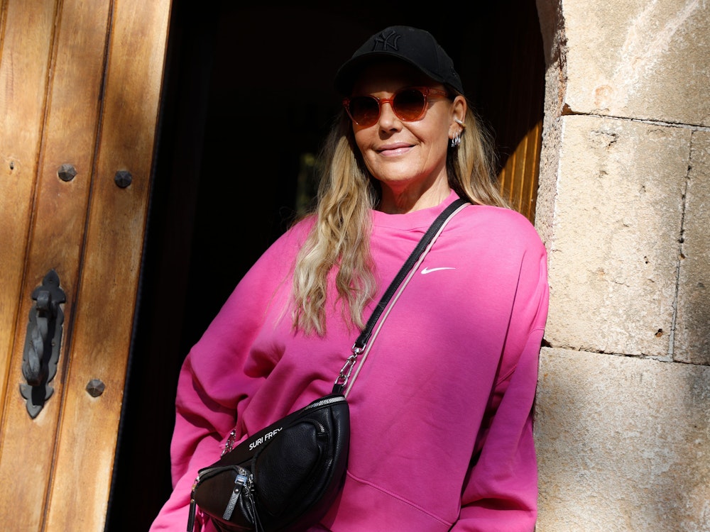 Natascha Ochsenknecht steht am 25. November 2021 in der Tür eines Hauses auf Mallorca in einem knallpinken Oberteil und trägt eine Sonnenbrille und eine schwarze Cap.