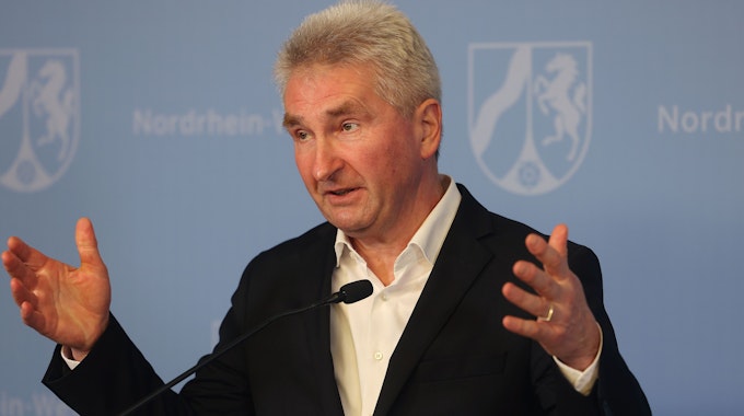 Andreas Pinkwart (FDP) mit erhobenen Händen im Anzug bei einer Rede am 21. Februar 2022.