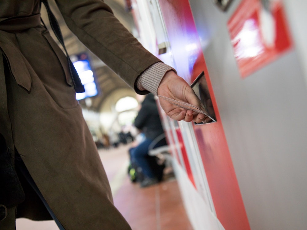 Eine Frau nimmt am 28. März 2018 ein Bahnticket aus einem Ticketautomaten.