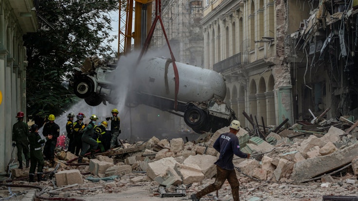 06.05.2022, Kuba, Havanna: Feuerwehrleute besprühen einen Tankwagen mit Wasser, um ihn zu kühlen, während sie ihn vom Ort einer tödlichen Explosion entfernen, die das Fünf-Sterne-Hotel Saratoga in Havanna, Kuba, zerstört hat.