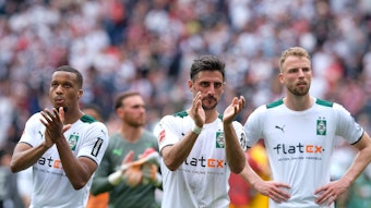 Gladbach-Kapitän Lars Stindl (M.), Alassane Plea (l.) und Marvin Friedrich (r.) blicken nach dem Schlusspfiff am Sonntag (8. Mai 2022) in Frankfurt Richtung mitgereister Borussia-Fans.