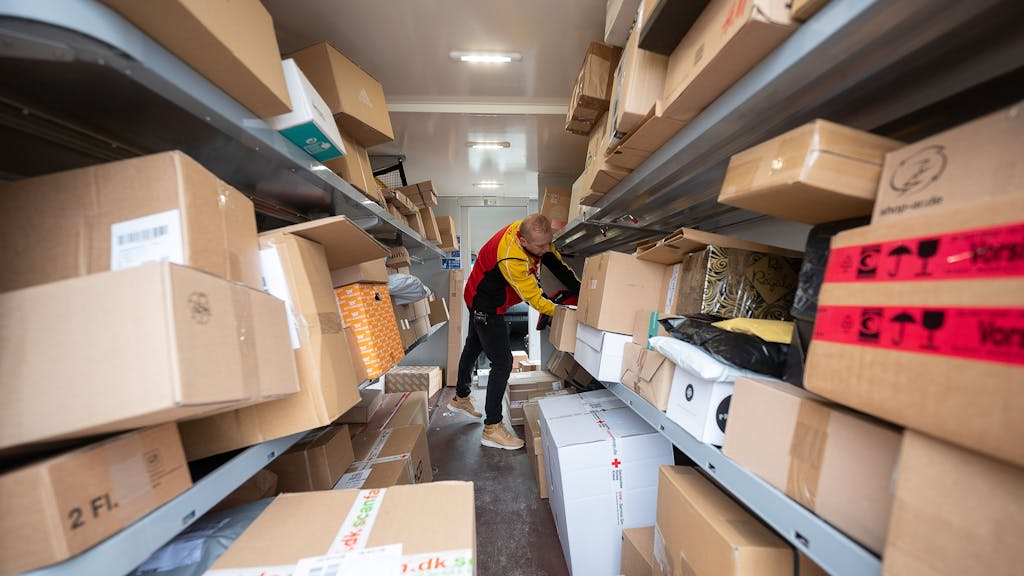 Ein DHL-Mitarbeiter sortiert am 15. Dezember 2021 in seinem Transporter die Pakete und Päckchen für die nächsten Zustellungen