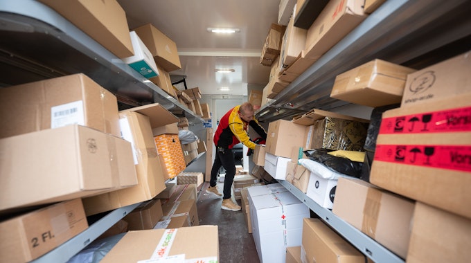Ein DHL-Mitarbeiter sortiert am 15. Dezember 2021 in seinem Transporter die Pakete und Päckchen für die nächsten Zustellungen