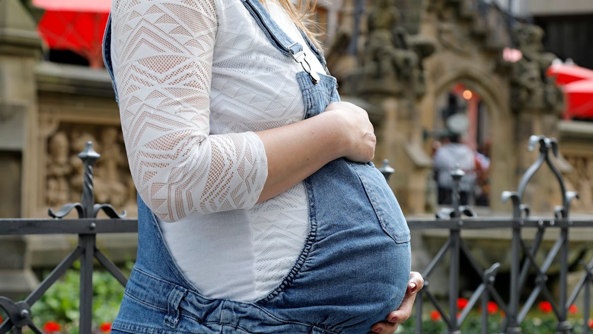 Eine schwangere Frau mit Babybauch von der Seite fotografiert