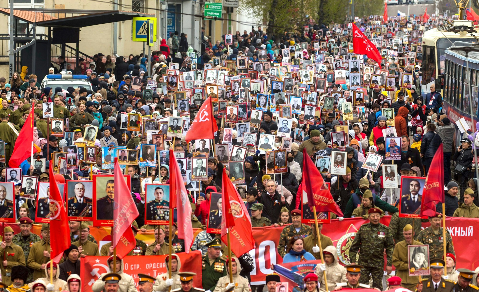 Menschen tragen zum „Tag des Sieges“ am 9. Mai 2022 in Ulan-Ude (Russland) ein Porträt des ehemaligen sowjetischen Führers Josef Stalin sowie Porträts von sowjetischen Führern und Verwandten, die im Zweiten Weltkrieg gekämpft haben. Auch russische und sowjetische Flaggen werden getragen.