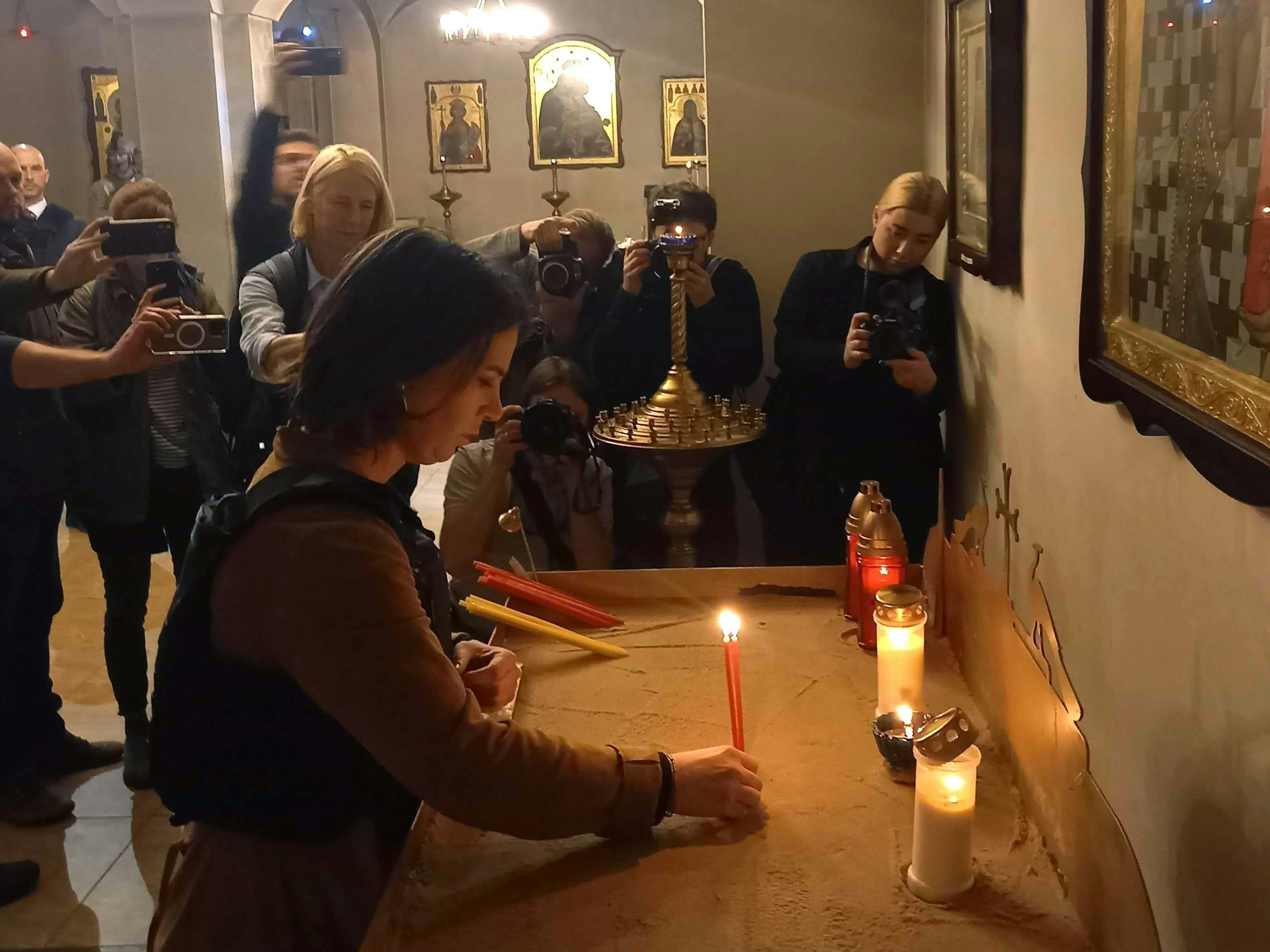 Außenministerin Annalena Baerbock (M, Bündnis 90/Grüne) entzündet am 10. Mai 2022 eine Kerze für die Opfer in einer Kirche in Butscha.
