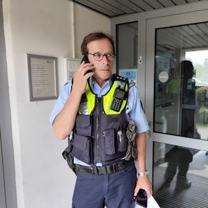 Polizist Sven Bartz telefoniert in einem Hauseingang.