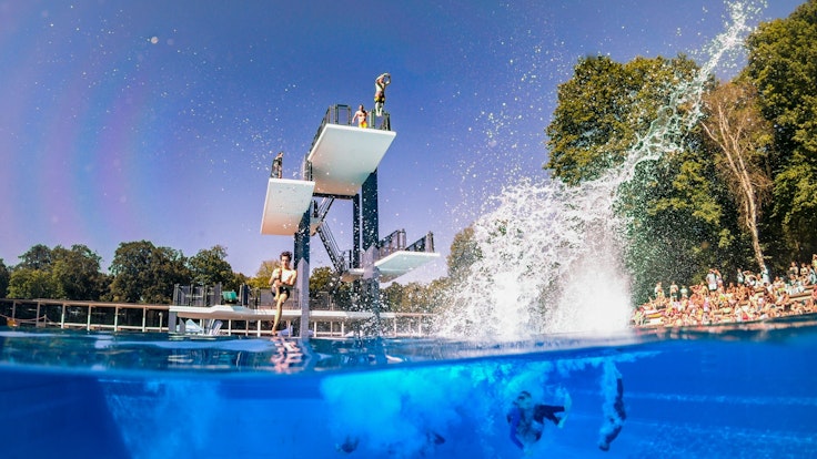 Turmspringer springen im Kölner Stadionbad ins Wasser.