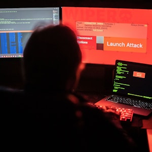 Das Symbolfoto vom 25.02.2022 aus Bad Oeynhausen (NRW) zeigt einen Mann vor Bildschirmen, die Hacker-Programme und eine fiktive Fernlösch-Software zeigen.