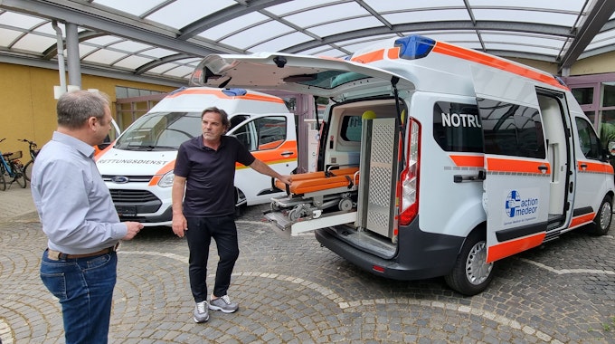 Volker Struth und Christoph Bonsmann mit dem Krankenwagen.